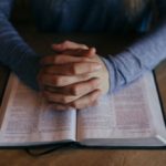 man holding his hands on open book